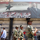 Assad beams down in Damascus in September 2006. The text reads, “Syria is protected by God.”